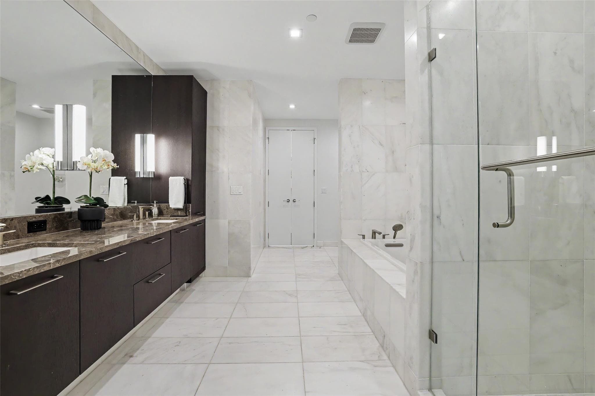 Marble finishes elevate this primary bathroom, fe