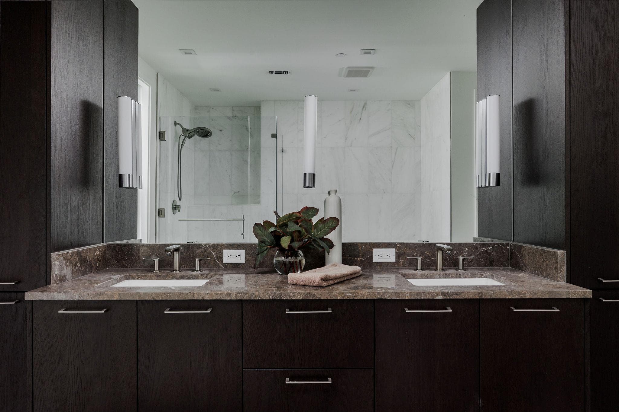 Double vanity with sleek dark cabinetry and polis