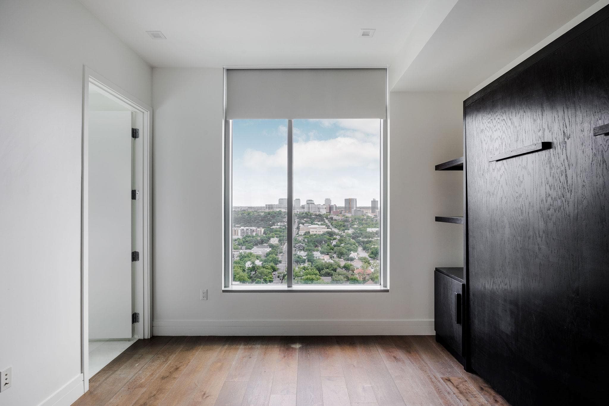 Hardwood flooring and large windows frame a capti