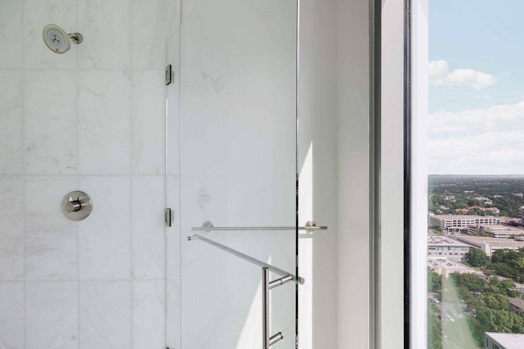Marble-clad shower with a glass enclosure offers