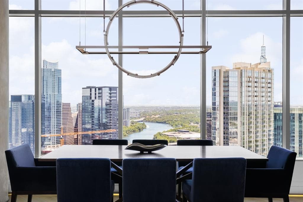 Dining area framed by floor-to-ceiling windows over downtown Austin at Fifth & West